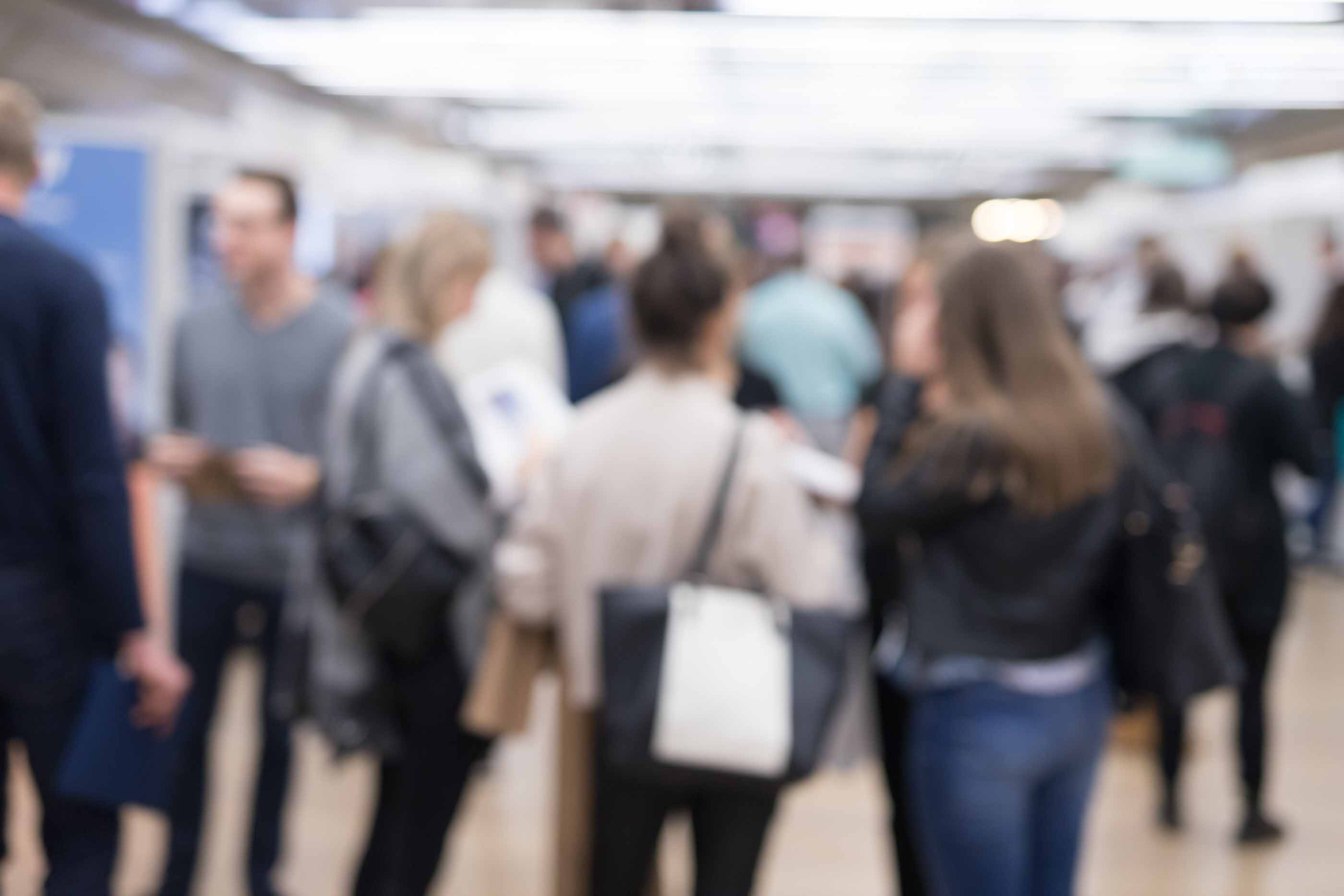 Verschwommene Aufnahme von Menschen auf einer Messe. 