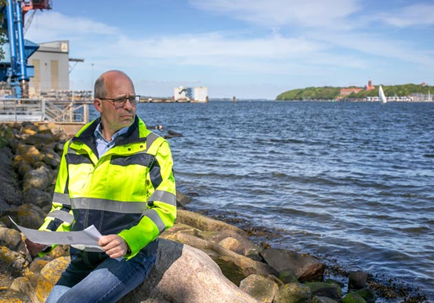 Mann in Warnweste am Meer, Übergang zur Fotostrecke